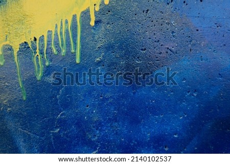 Blue painted stucco concrete with leaking traces of yellow paint. Abstract old grunge wall texture banner background