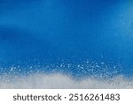 Blue painted wall texture with white spray paint splattering upwards, providing copy space