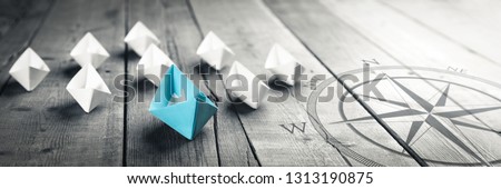 Blue Paper Boat Leading A Fleet Of Small White Boats With Compass Icon On Wooden Table With Vintage Effect - Leadership Concept	