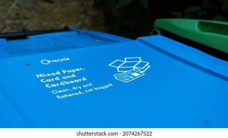 A Blue Paper Recycling Trash Can In A Garden With Instructions Written On The Lid