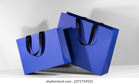 Blue paper shopping bags mockup with black handles on grey background