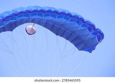 Blue parachute deployed while descending in the sky
