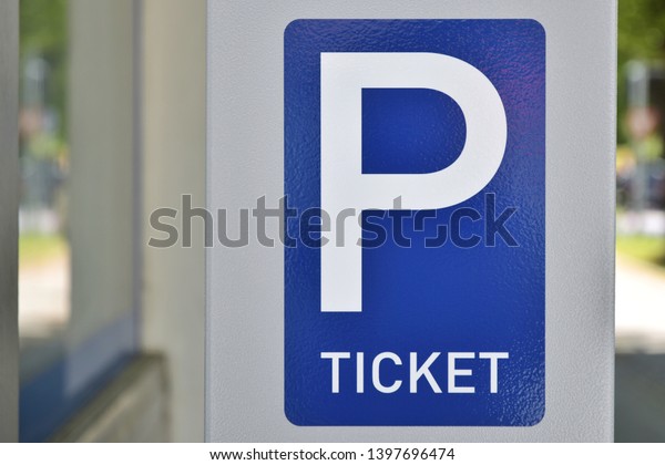 Blue parking sign with a big P and inscription\
ticket. Blue and white metal parking ticket dispensing sign.\
Automatic dispensing machine for park tickets. Sign of parking\
tickets on a city street