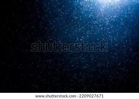 Blue particles on black background with cinematic atmosphere. Glittering sparkling bokeh overlay with copy space for text.