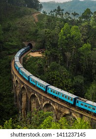Blue passenger train passing the famous and iconic Nine Arches Bridge near Ella, Sri Lanka