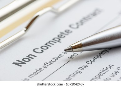 Blue pen and a non compete contract on a clipboard. Noncompete contract is an agreement between employee and employer, not to enter into competition in subsequence business effort. Legal form concept.