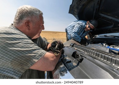 Blue pickup truck breaks down on the shoulder of a freeway while two men try to assess the problem. - Powered by Shutterstock