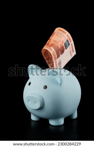 Blue piggy bank and banknote of 5000 Russian rubles on a black background