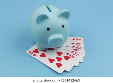 Blue piggy bank and hearts playing cards on blue background. 