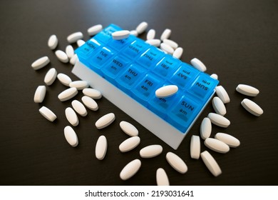 Blue Pil Lbox On A Black Table. Tablets Lie On The Covers Of The Cells Of Different Days Of The Week. Pill Storage Box