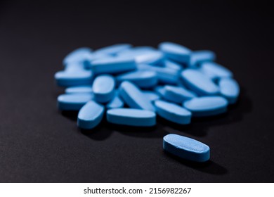Blue pill in the foreground and blurry background heap of blue colored tablets