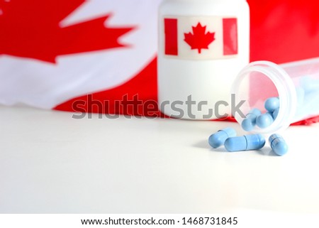 Blue pills flowing from container with Canadian flags in background.  Concept of how much cheaper prescription drugs are in Canada than in the United States