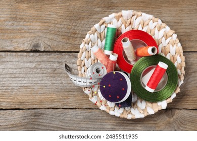 Blue pincushion with pins and other sewing tools on wooden table, top view. Space for text - Powered by Shutterstock