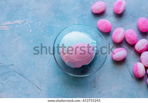 Blue and pink bubble gum ice cream with sweet candy cane\
on table background. Summer food content. Copy space, top view.\
