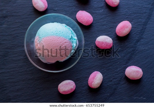 Blue and pink
bubble gum ice cream with sweet candy cane on dark slate table
background. Summer food
content