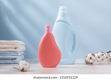 Blue and pink plastic bottle of laundry detergent with cotton towels and branch of cotton in the background. Delicate wash concept - Shutterstock ID 2316931129