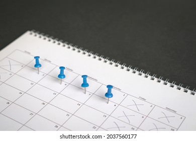 Blue pins on four days in a week on a calendar. Friday, Saturday and Sunday crossed out. Four day work week concept. - Shutterstock ID 2037560177