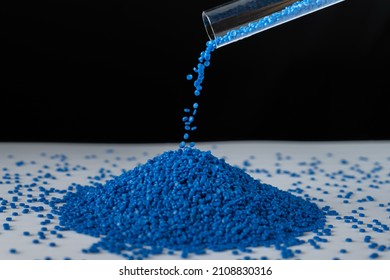 Blue plastic beads on wood  background, Polymers bead or polymer resin, polymer pallet, Product from petrochemical plants. granules polymer, Concept roof of house is made of polymer plastic.