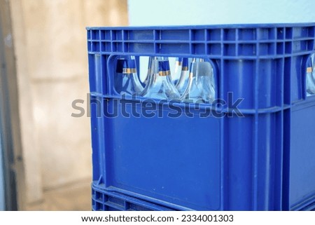 Blue plastic beer crate with empty bottles