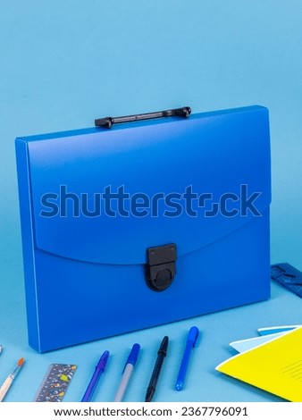 Blue plastic  briefcase folder for documents and school items on a bright blue table