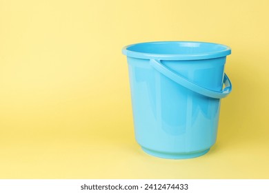 A blue plastic bucket on a yellow background. A container for storing liquids. - Powered by Shutterstock