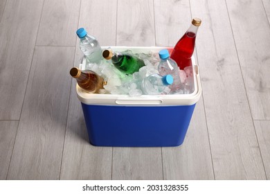 Blue Plastic Cool Box With Ice Cubes And Refreshing Drinks On Wooden Floor