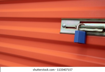 Blue Plastic Lock On An Orange Self Storage Unit Door.