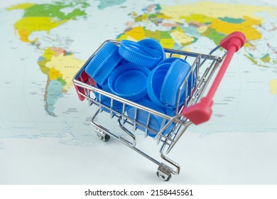 Blue Plastic Pet Bottle Cap On Supermarket Trolley In Front Of World Map, Make Money From Recycle, Plastic Pet Bottle Recycle Concept, Shopping Plastic Idea, Selling Recycled Plastic, Top View