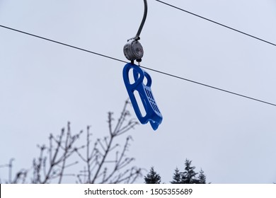 Blue Plastic Sled Is Hanging On A Toboggan Lift. Torfhaus In Harz Mountains National Park, Germany