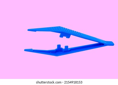 Blue Plastic Sterile Surgical Tweezers Isolated On Pink Background.