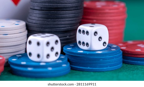 Blue poker chips support two white dice. Red and black stacks stand behind them. Green felt surface frames the setup. Dice display black dots clearly. Ideal for casino promotion
