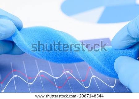 Blue porous foam material twisted in scientist hands in laboratory. Research for material with new properties concept.