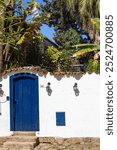 Blue portal in the white wal of a historic house whit stone steps in the historic center of Praty , Rio de Janeiro, Brasil.