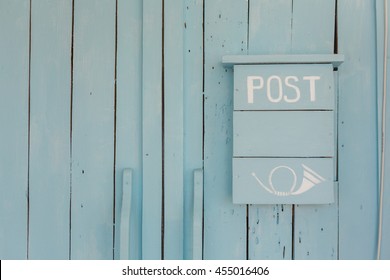 Blue post box on a wooden blue wall 