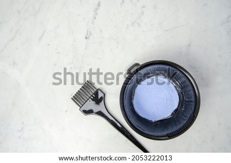 Blue powder hair dye bleaching tools with gloves, comb and brush on marbled background