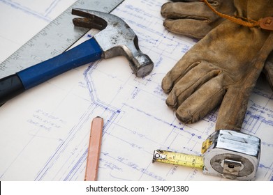 Blue Prints At A Work Site With Tools And Gloves