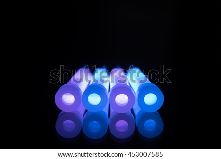 Blue and purple glowsticks in a row on a reflective surface