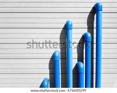 Blue PVC pipes emerge from a gray wooden wall with horizontal lines
