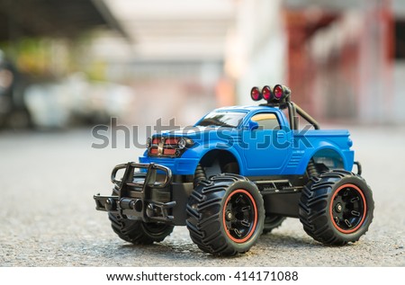 Blue RC Off road truck car (Radio-controlled) on the asphalt ground. This toy have some dust from children playing.