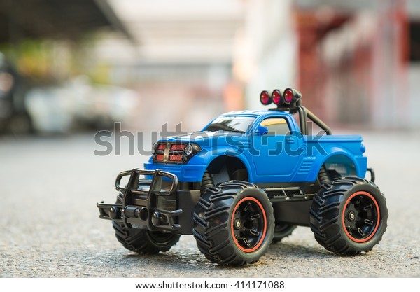 Blue RC\
Off road truck car (Radio-controlled) on the asphalt ground. This\
toy have some dust from children\
playing.