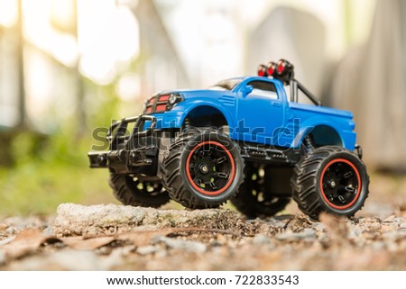 Blue RC Off-road truck car (Radio-controlled) standing on the rock and terrain sand dune. This toy has some dust from children playing.