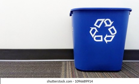 A Blue Recycle Bin Sits On The Floor Of An Office.