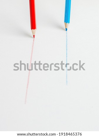Blue and red pencils drawing parallel lines on a white background. The concept of cooperation.
