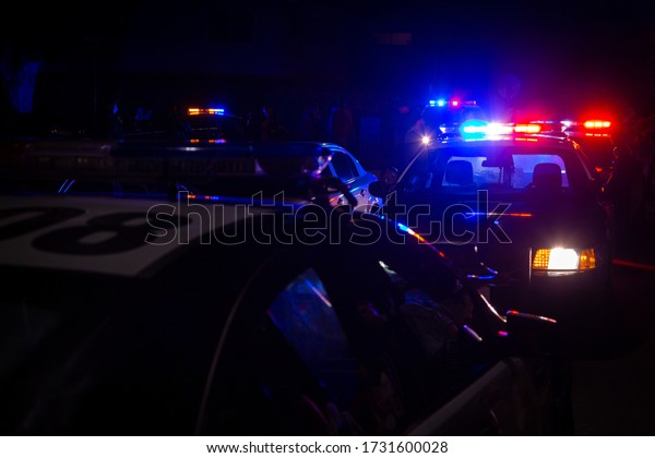 Blue and red police\
lights on squad cars during a night time traffic stop, with space\
for text on the left