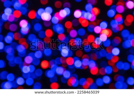 Blue, red and purple circles of lights on a black background (strong bokeh effect)