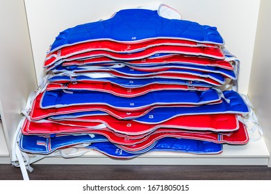 Blue And Red Taekwondo Protective Gear Is Stacked.  Protectors, Vests. Blue And Red Protective Gear Of Different Sizes For Taekwondo Lies In A Pile.  Protectors, Vests.