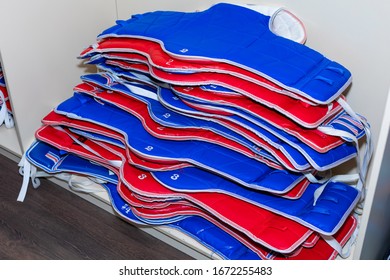 Blue And Red Taekwondo Protective Gear Is Stacked.  Protectors, Vests. Blue And Red Protective Gear Of Different Sizes For Taekwondo Lies In A Pile.  Protectors, Vests.