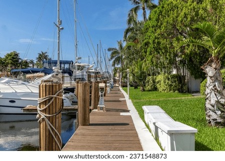 Blue Reflecting Canal in Florida Usa. Reflecting Water Canal with Public  Harbors for Private Boats under Clear Blue Sky with some Clouds. Large amounts of Diverse Vegetation around the Canal;.