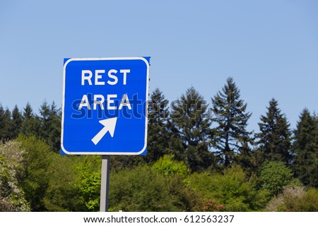 Blue rest area sign points to a highway exit where drivers can relax and rest during their travel.