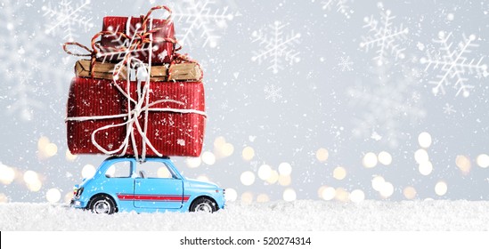 Blue retro toy car delivering Christmas or New Year gifts on festive gray background